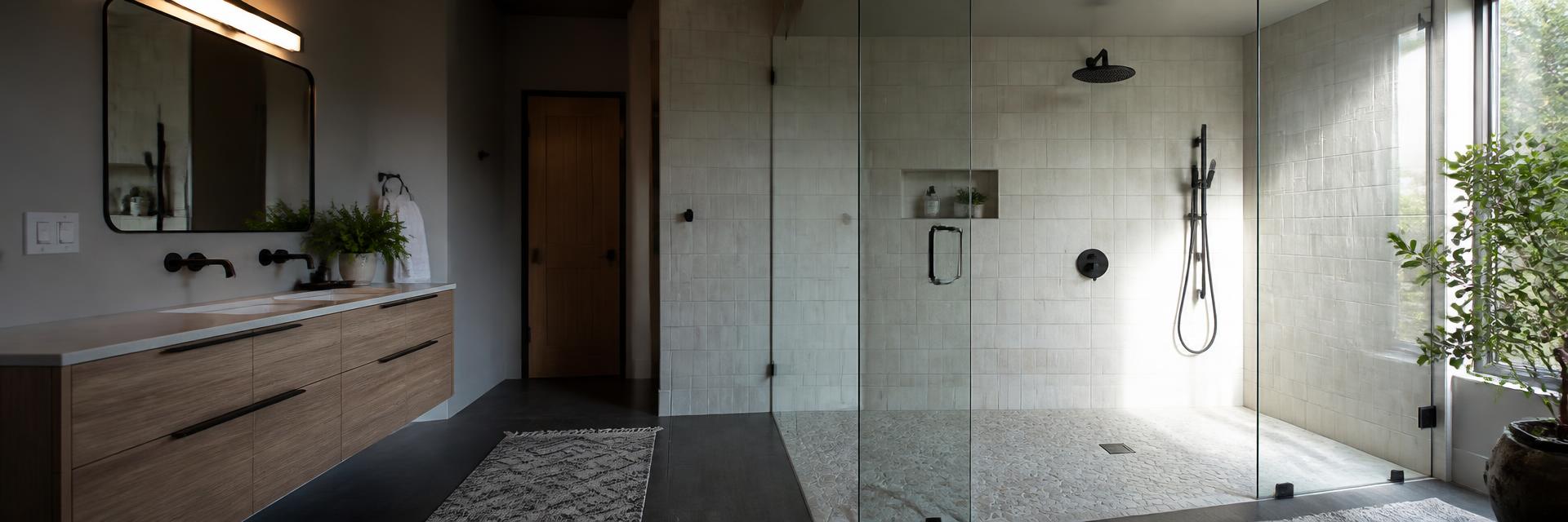 Modern bathroom remodel with walk-in tiled shower, glass panel, floating wood vanity and matte black fixtures
