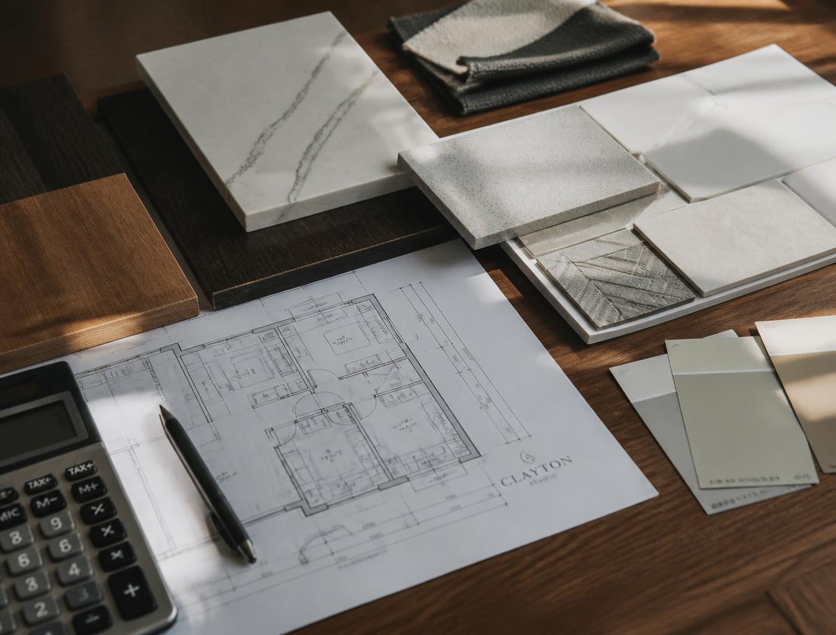 Remodeling blueprints with tile, quartz and paint samples on a wood table