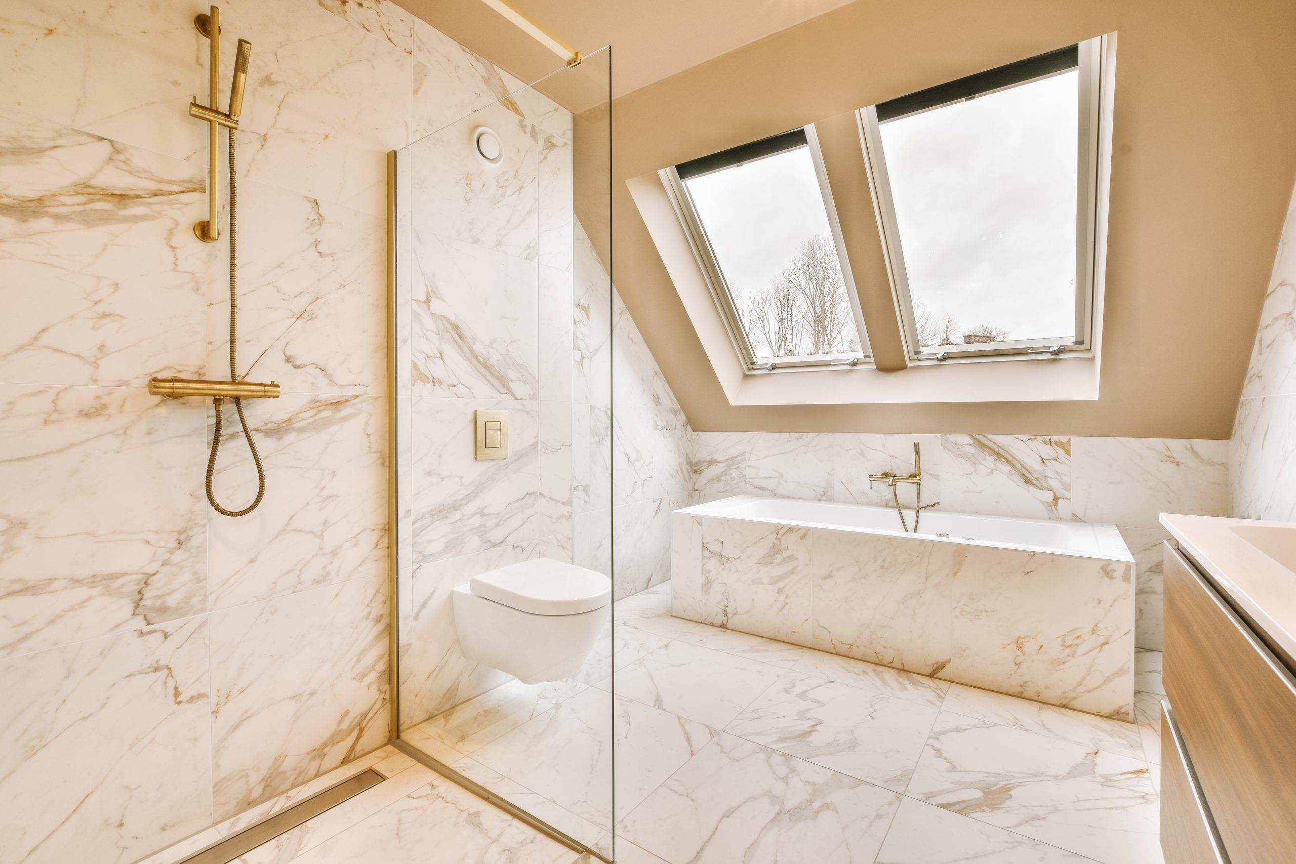 Marble bathroom with glazed shower, bathtub, toilet and window view in a modern house